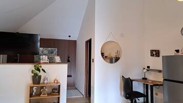 Una cocina moderna con comedor, un espejo redondo y un televisor en la pared.