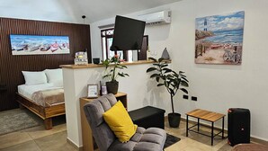 Un salon moderne avec un canapé, une petite table, un téléviseur et un tableau accroché au mur.