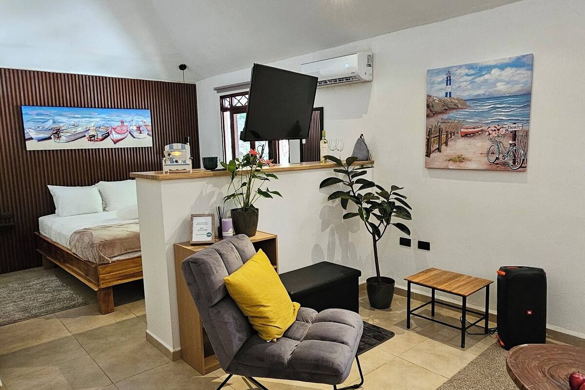 Een moderne woonkamer met een bank, een klein tafeltje, een televisie en een schilderij aan de muur.