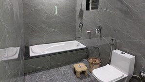 Uma casa de banho moderna com uma banheira grande, sanita e zona de duche.