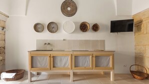 A bathroom with a wooden vanity, a mirror, and a mounted television.