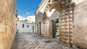 A cobblestone street with stone buildings, a bicycle, and a gate.