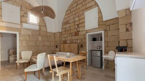 A dining area with a wooden table and chairs, a refrigerator, and a small kitchenette.