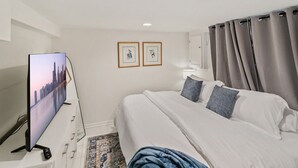 Une chambre d’hôtel avec un lit, une télévision, un bureau avec un ordinateur et deux tableaux encadrés au mur.