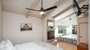 Ein Schlafzimmer mit Bett, Kamin, großem Spiegel und Deckenventilator.