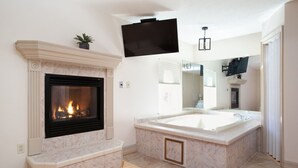 Ein modernes Badezimmer mit Kamin, einer großen Badewanne und einem Spiegel.