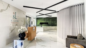 A modern reception area with a marble floor, a reception desk, a piano, and a green wall. - SkyView Penthouse by LovelyStay (Funchal)