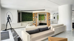 A modern living room with a sofa, a coffee table, and a unique wooden bookshelf structure. - SkyView Penthouse by LovelyStay (Funchal)