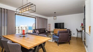 Una sala moderna con una mesa de comedor de madera, sofás de cuero y un televisor.