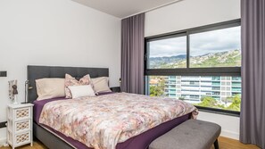 Una camera da letto con un letto grande, una panca, un comodino e una finestra con vista sulla città.