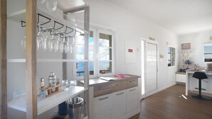 A modern kitchen with white cabinets, a wooden countertop, and a glass wine rack. - Ozeanica Heights by LovelyStay (Gaula)