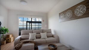 A living room with a sofa, a coffee table, and decorative wall art. - Ozeanica Heights by LovelyStay (Gaula)