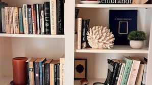 A bookshelf with various books, a candle, and decorative items.