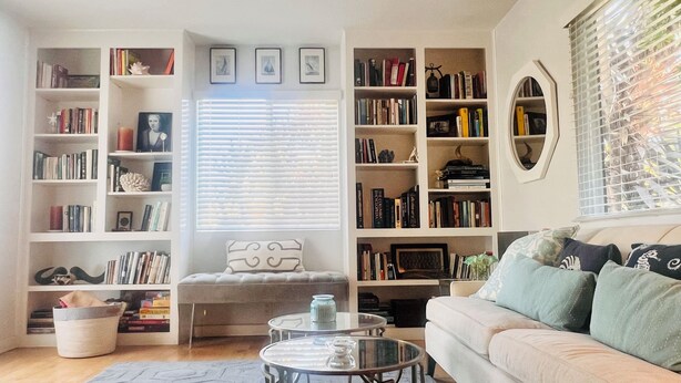 A cozy living room with a sofa, a coffee table, and a bookshelf filled with books.