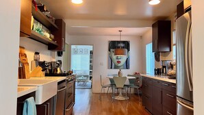 A modern kitchen with stainless steel appliances, wooden cabinets, and a dining area with a table and chairs.