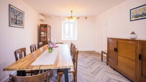 A dining room with a wooden table, chairs, a chandelier, and a cabinet. - Residence Villa Mima (Cavtat)