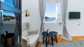 A room with a white sofa, a small round table, a gold floor lamp, and a window with curtains. - Residence Villa Mima (Cavtat)