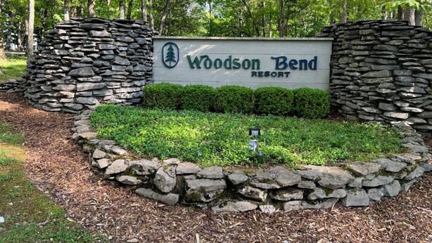 Skiltning for Woodson Bend Resort omgivet af stenvægge og grønt.