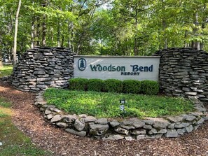 Un letrero de Woodson Bend Resort rodeado de muros de piedra y follaje.