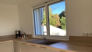 Cocina moderna con ventana, pileta y mostrador.