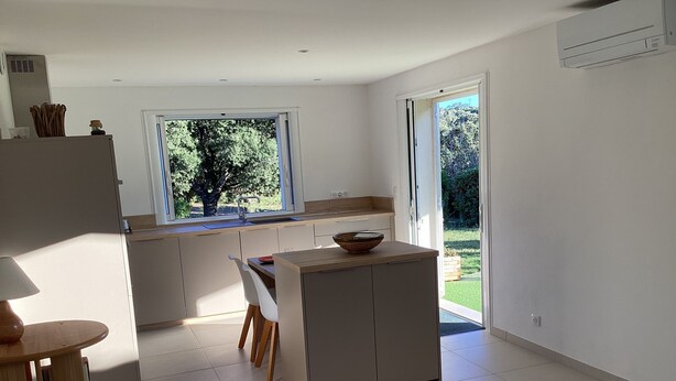 Una cocina moderna con un ventanal grande, un comedor con mesa y sillas, y vistas al exterior.