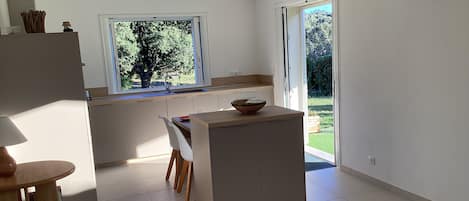 Una cocina moderna con un ventanal grande, un comedor con mesa y sillas, y vistas al exterior.