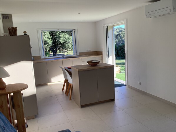 Una cocina moderna con un ventanal grande, un comedor con mesa y sillas, y vistas al exterior.
