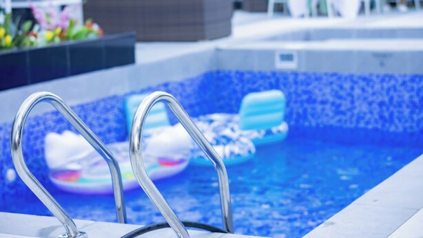 A swimming pool with metal ladders, blue mosaic tiles, and inflatable pool floats. - Pinorich Villa (Buea)