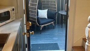 Une cuisine équipée d’un four à micro-ondes, d’une chaise en osier et d’une petite table avec un coussin.