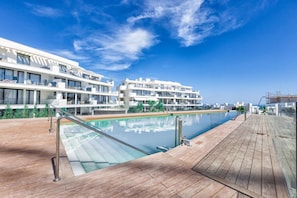 A modern hotel with a pool, wooden deck, and balconies overlooking the sea. - Aurelia | Private Garden - Pool - Gym (Fuengirola)