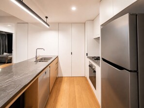 Una cocina moderna con encimera de mármol, electrodomésticos de acero inoxidable y suelo de madera.