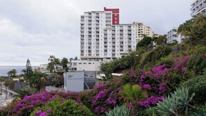 A coastal hotel with multiple floors, balconies, and lush greenery. - Apartamentos do Mar - Pikis Flat (Funchal)
