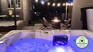 An outdoor hot tub area with string lights, a fire pit, and seating. - Flagstaff Forest Retreat • Hot Tub • Fire Pit • Fully Fenced Yard • P... (Flagstaff)