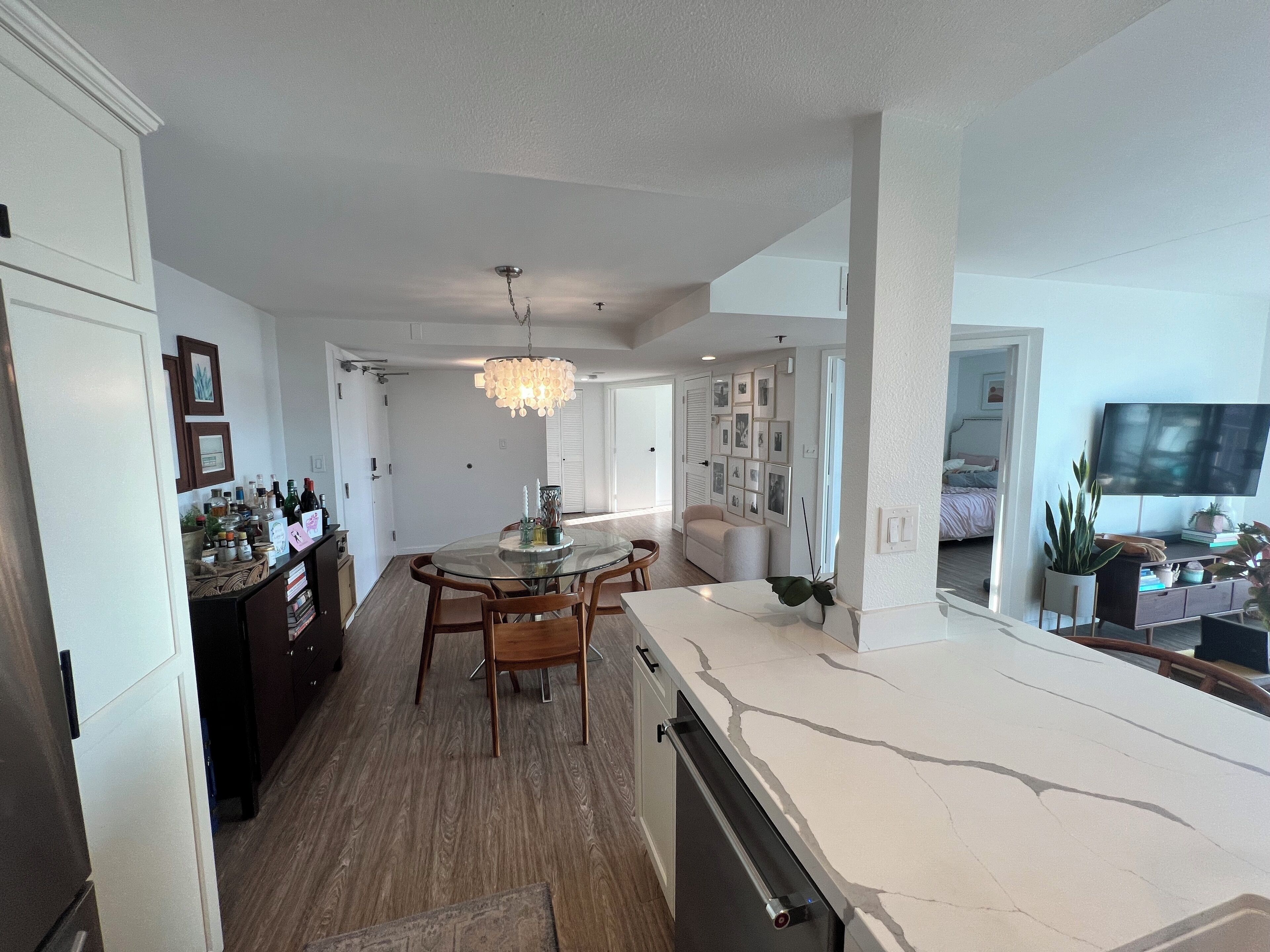 Une cuisine moderne avec un îlot central, un plancher en bois et un lustre.