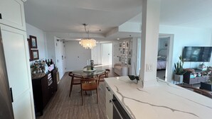 A modern kitchen with a central island, wooden flooring, and a chandelier. - Urban Oasis with Sweeping Views - Walk to Gaslamp, Little Italy, Balboa Park (San Diego)