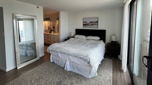 A bedroom with a large bed, a walk-in closet, a bathroom with a vanity, and a view through a sliding door. - Urban Oasis with Sweeping Views - Walk to Gaslamp, Little Italy, Balboa Park (San Diego)