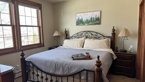 Een slaapkamer met een groot bed, twee nachtkastjes, een raam en een schilderij aan de muur.