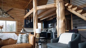 Een gezellig houten interieur met een eettafel, een keuken met moderne apparatuur en een open haard.