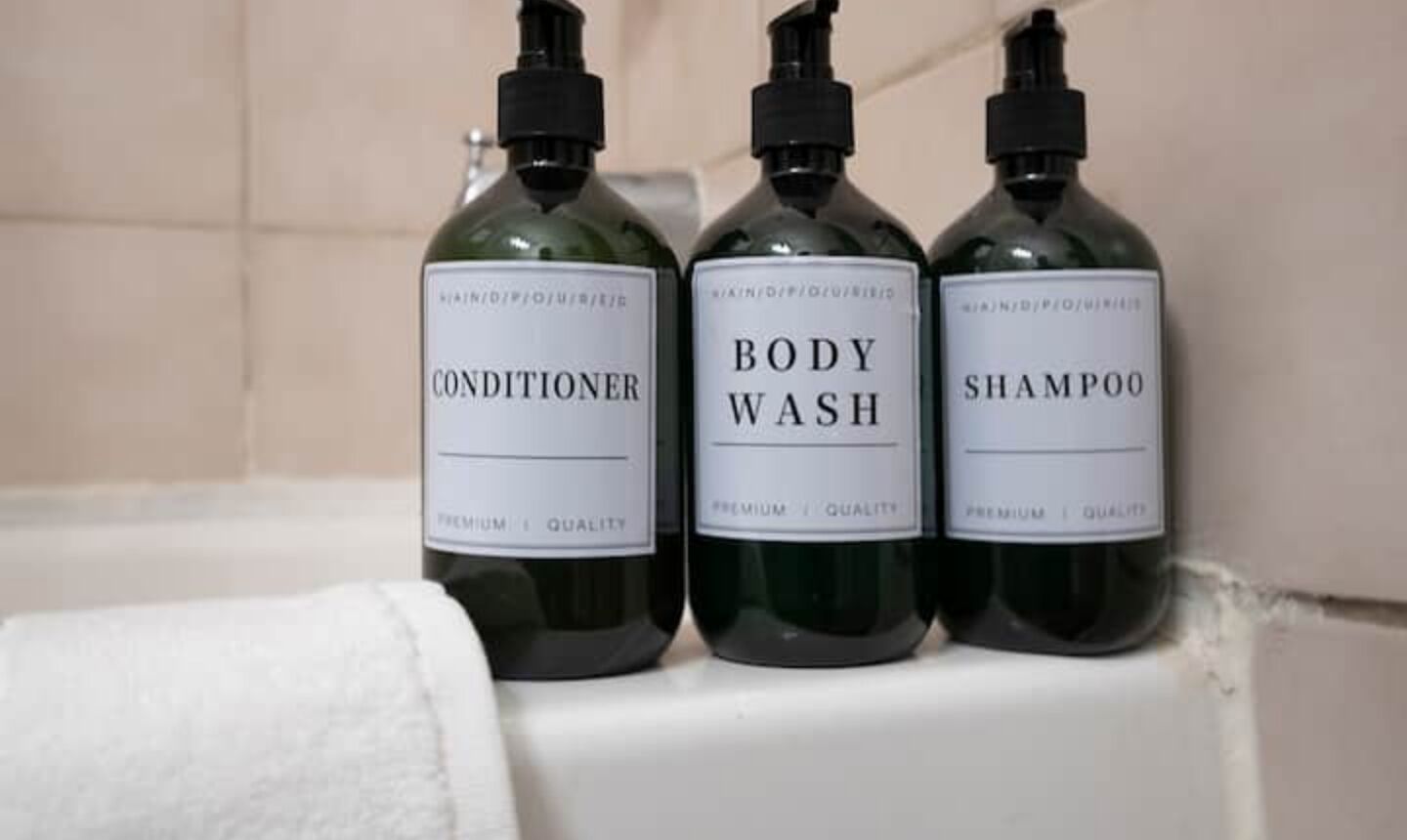 Tres botellas de gel de baño, acondicionador y champú sobre una repisa del baño.