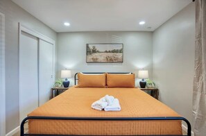 A bedroom with a bed, two bedside tables, a painting on the wall, and a curtain on the window. - Walk to Old Town! Hot Tub • Game Room • Glow Golf • Pet Friendly • Sl... (Scottsdale)