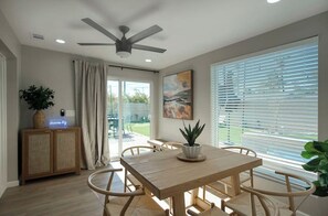 A dining area with a wooden table and chairs, a ceiling fan, a potted plant, and a view through a glass door to the outside. - Walk to Old Town! Hot Tub • Game Room • Glow Golf • Pet Friendly • Sl... (Scottsdale)