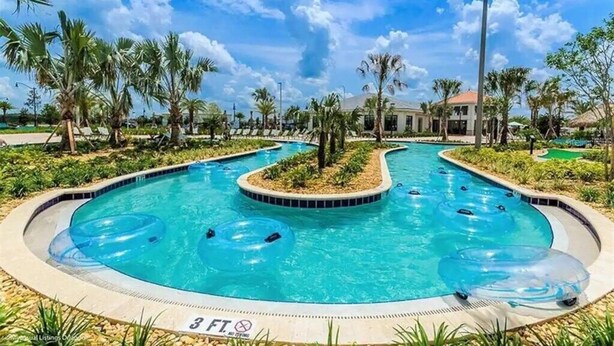 A swimming pool with multiple lanes, surrounded by palm trees and a building in the background. - Amazing 7 BR STOREY LAKE RESORT, ideal location, close to everything 2801 (kissimmee)
