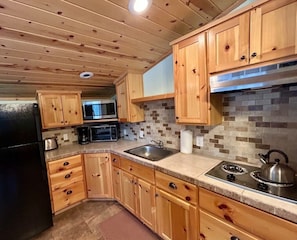 A kitchen with wooden cabinets, a microwave, a stove, and a sink.
