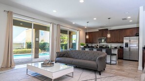 A modern kitchen with a refrigerator, microwave, and island. - 421 NP - Exquisite Retreat at Encore Resort (Kissimmee)