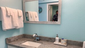 A bathroom with a marble sink, a mirror, and a towel rack.