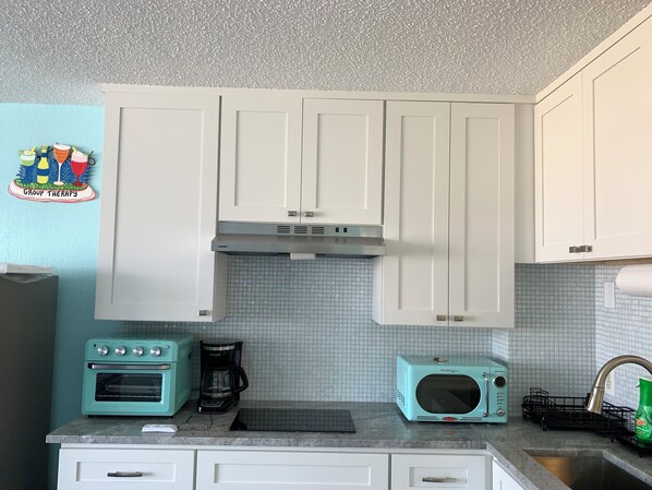 Uma cozinha com armários brancos, micro-ondas, forno e máquina de café.