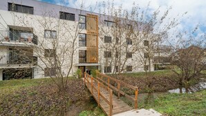 Un bâtiment moderne avec un pont en bois menant à une entrée fermée par un portail.