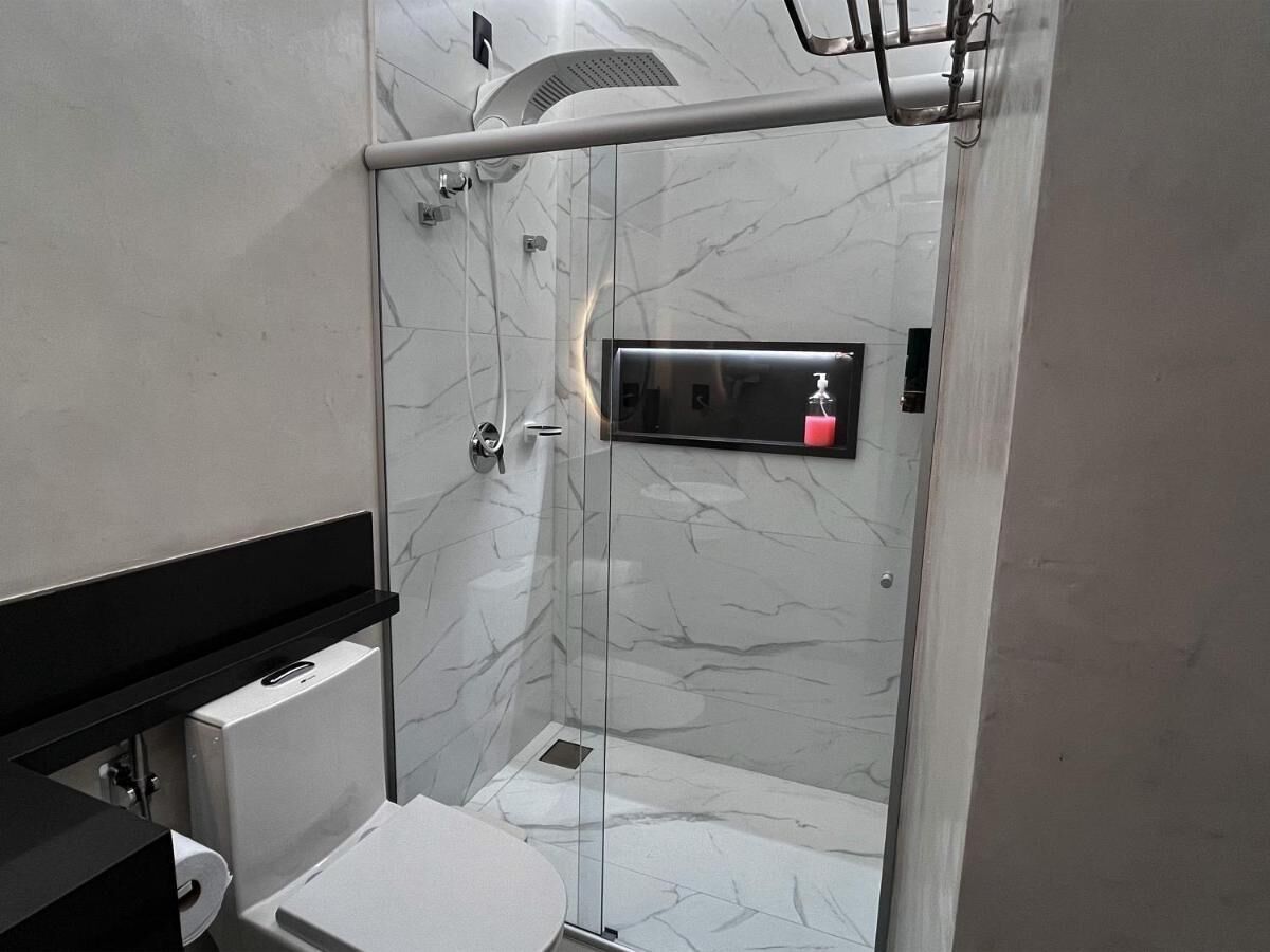 A modern bathroom with a glass shower enclosure, a black countertop, and a white sink.