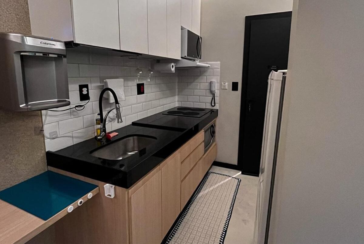 Una cocina compacta con encimera negra, electrodomésticos de acero inoxidable y un microondas.
