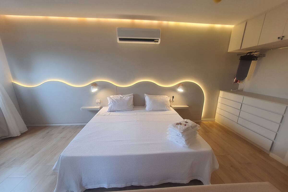 Une chambre à coucher moderne avec un lit, des tables de chevet et une armoire intégrée.